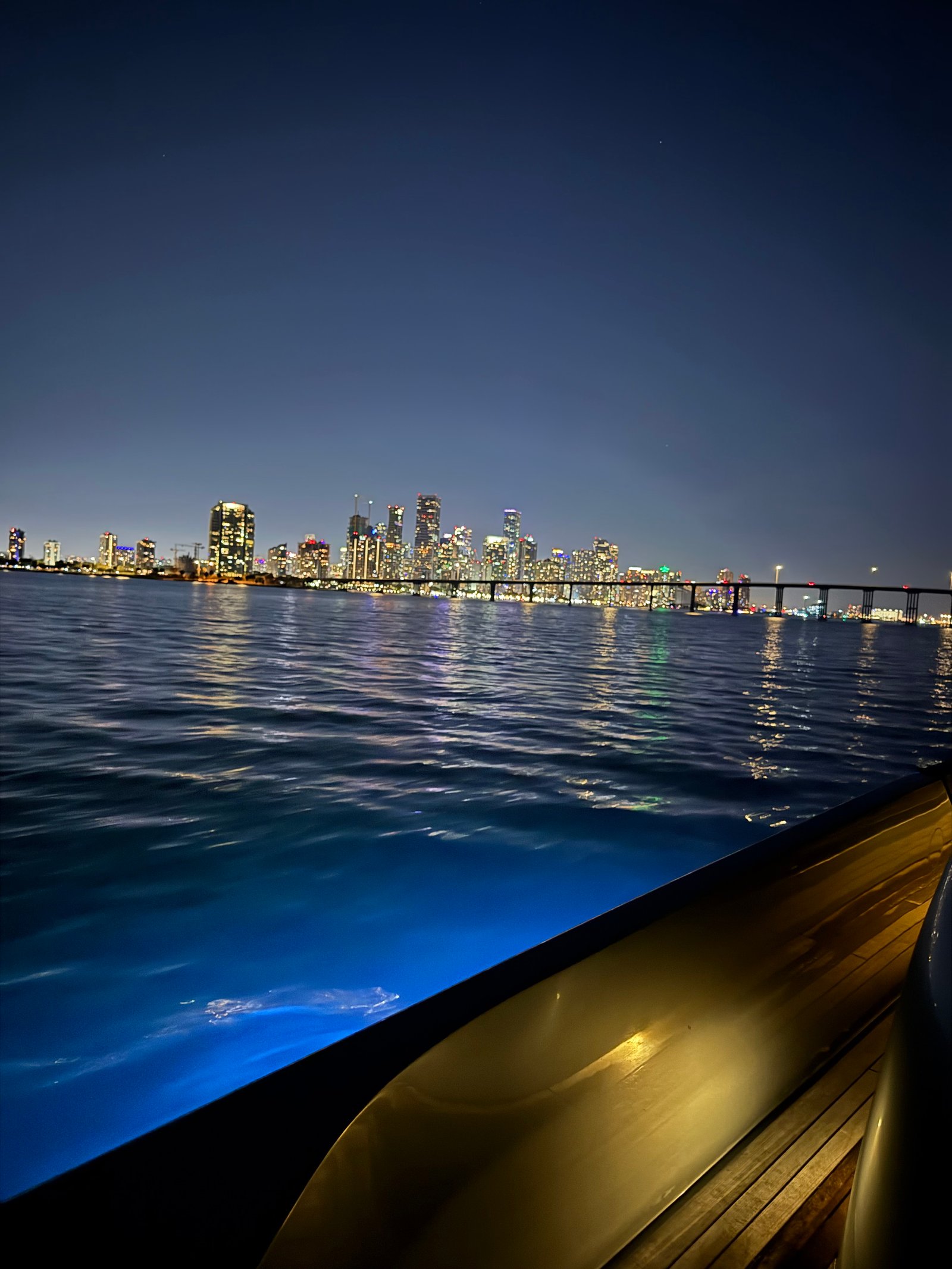 El yate de noche frente al skyline de Miami y el puente de Rickenbacker