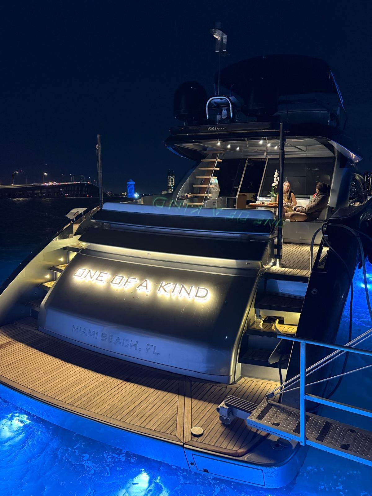 Popa del yate iluminada con el nombre One of a Kind, Miami Beach